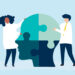 Image of People connecting jigsaw pieces of a head together. Mental health concept
